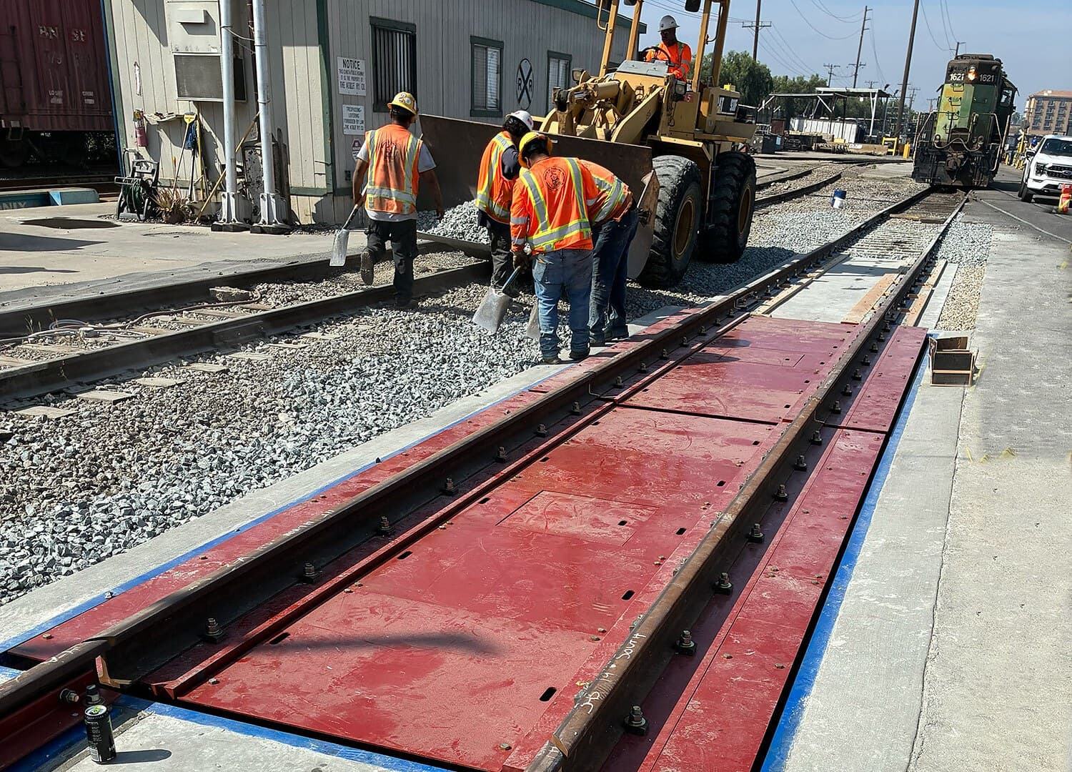 Crew working beside a rail scale weighbridge set into the track